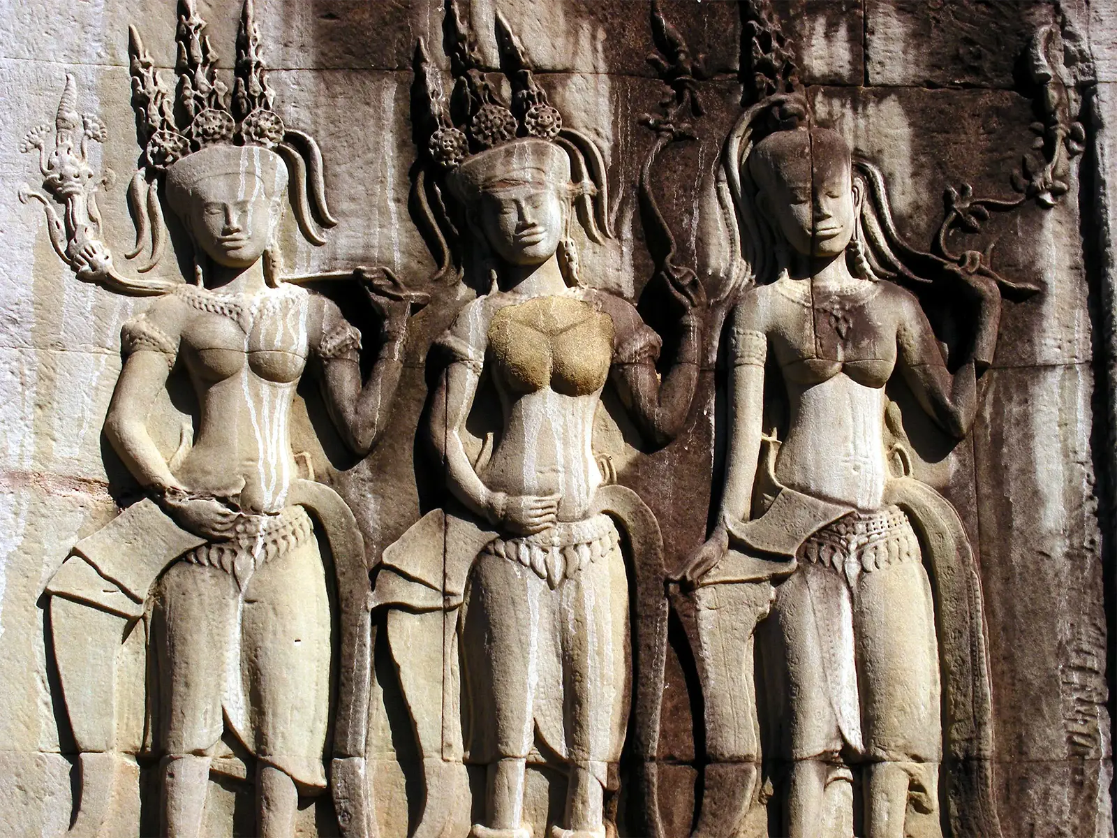 Trois devatas sculptées en bas-relief sur un mur de grès d’Angkor Wat