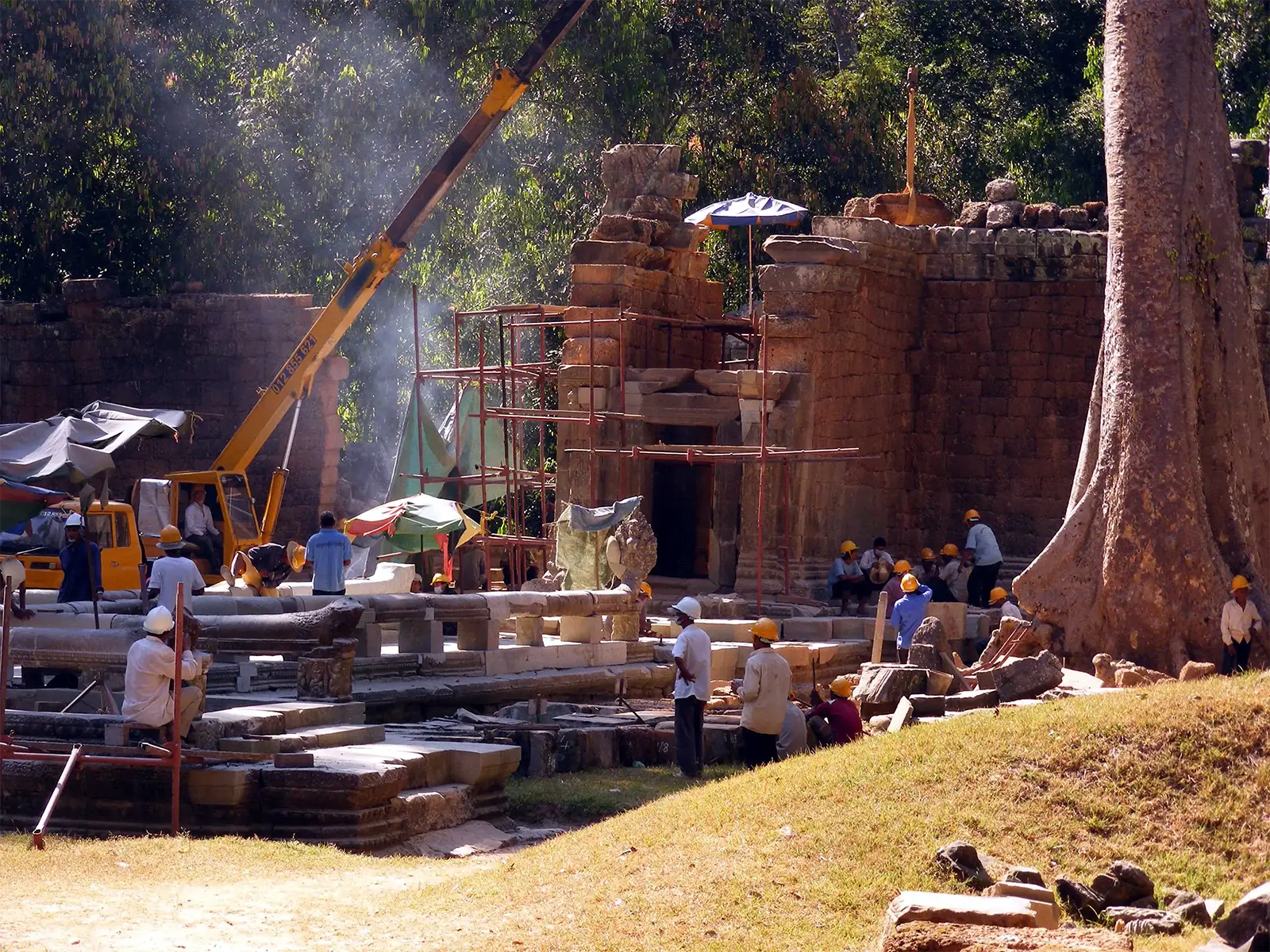 Ouvriers casqués et grue sur un chantier de restauration d’un temple d’Angkor