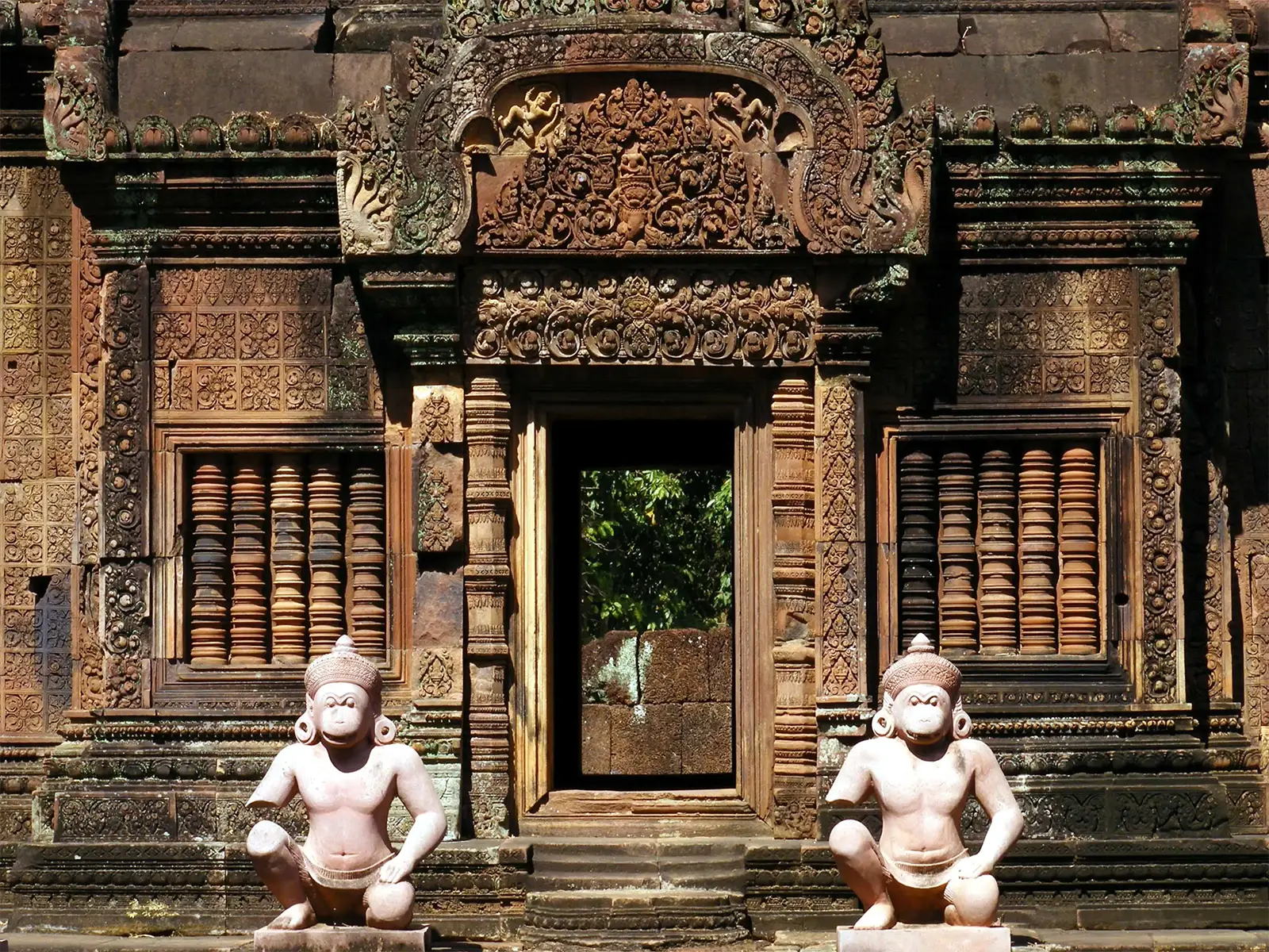 Gardiens à tête de singe devant une porte finement sculptée du temple de Banteay Srei