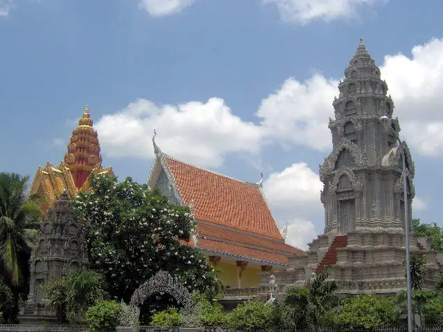 Pagode aux toits orange et stupa khmer sculpté sous un ciel nuageux à Phnom Penh