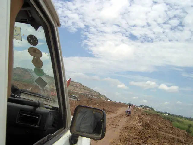 Piste de terre rouge à travers la campagne cambodgienne, vue depuis un véhicule