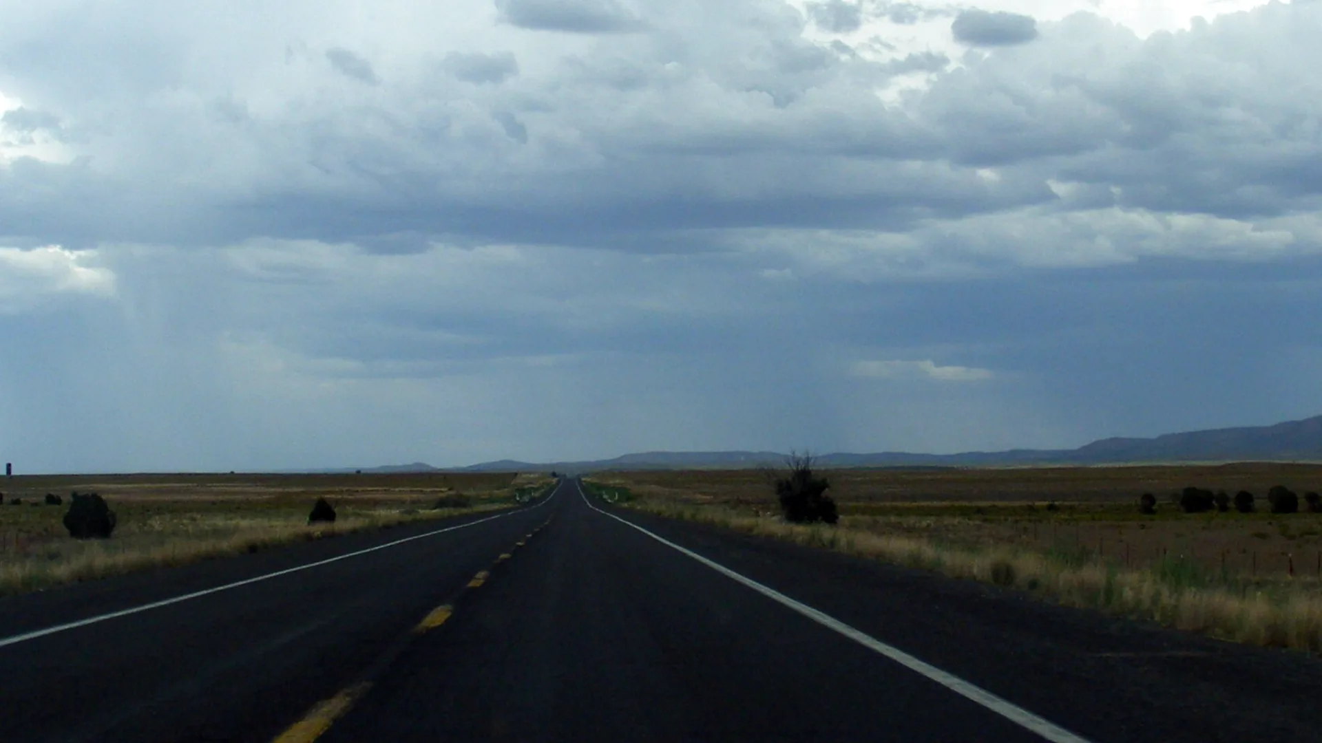 Route toute droite à travers les plaines de l’Arizona sous un ciel d’orage, en route vers le Grand Canyon