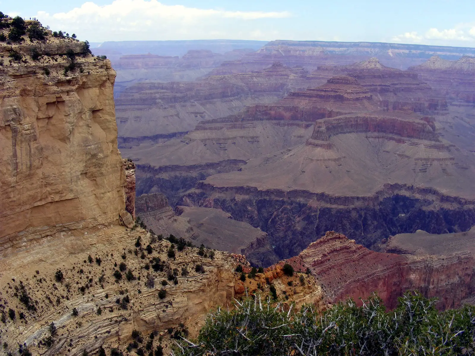 Haute falaise ocre et buttes en gradins du Grand Canyon sous un ciel bleu nuageux
