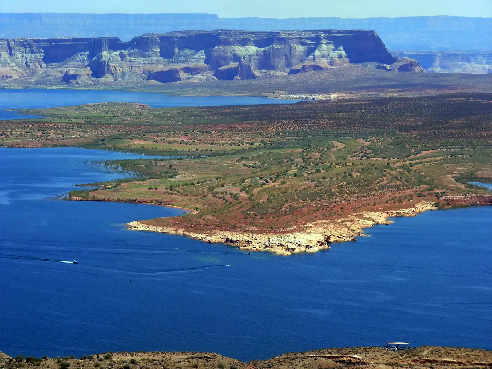 Presqu’île verdoyante sur le lac Powell et longue mesa de grès à l’horizon, près de Page