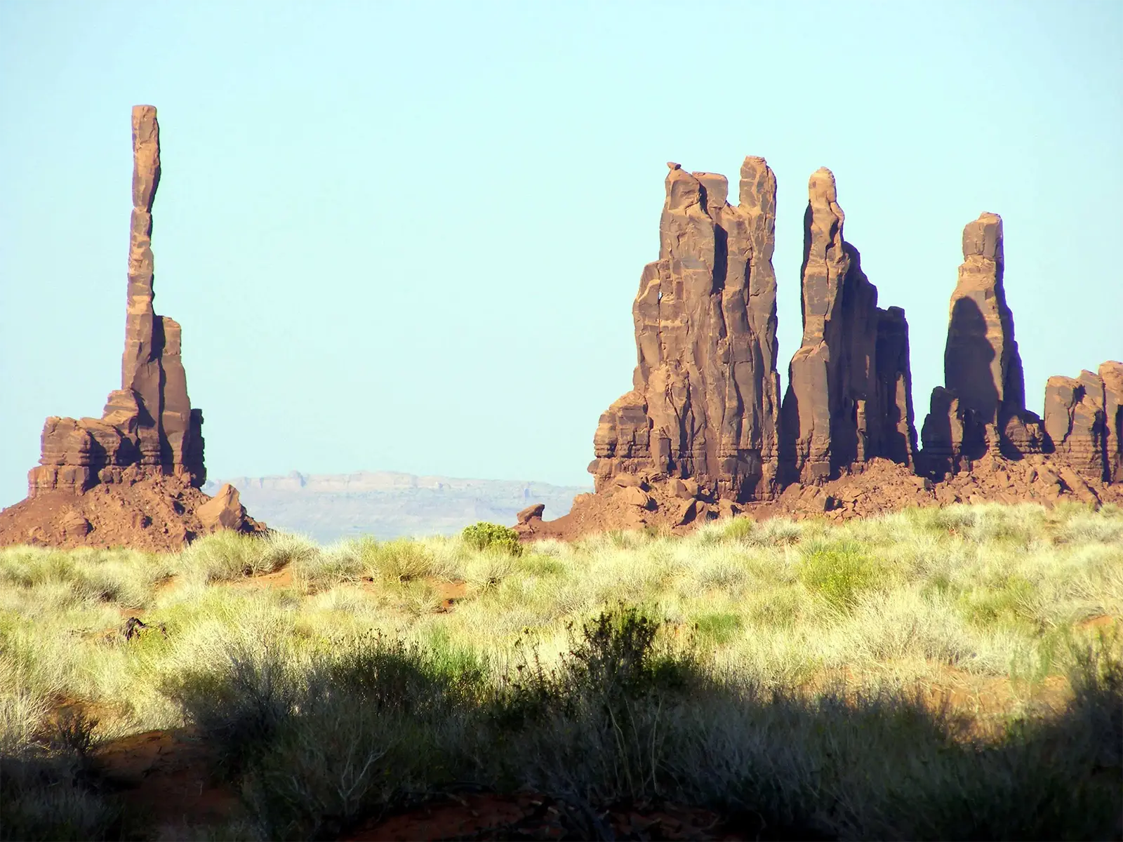 Les aiguilles du Totem Pole et des Yei Bi Chei au-dessus des herbes hautes de Monument Valley