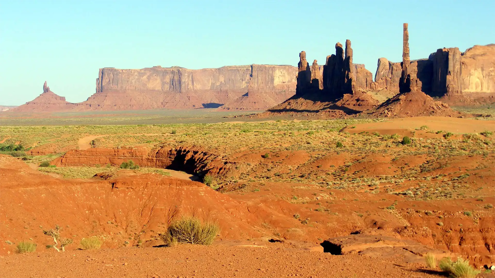 Le Totem Pole, les longues mesas et les dunes de sable rouge de Monument Valley en fin de journée