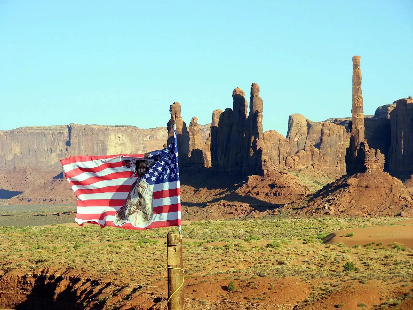 Drapeau américain orné d’un portrait amérindien flottant devant le Totem Pole, à Monument Valley