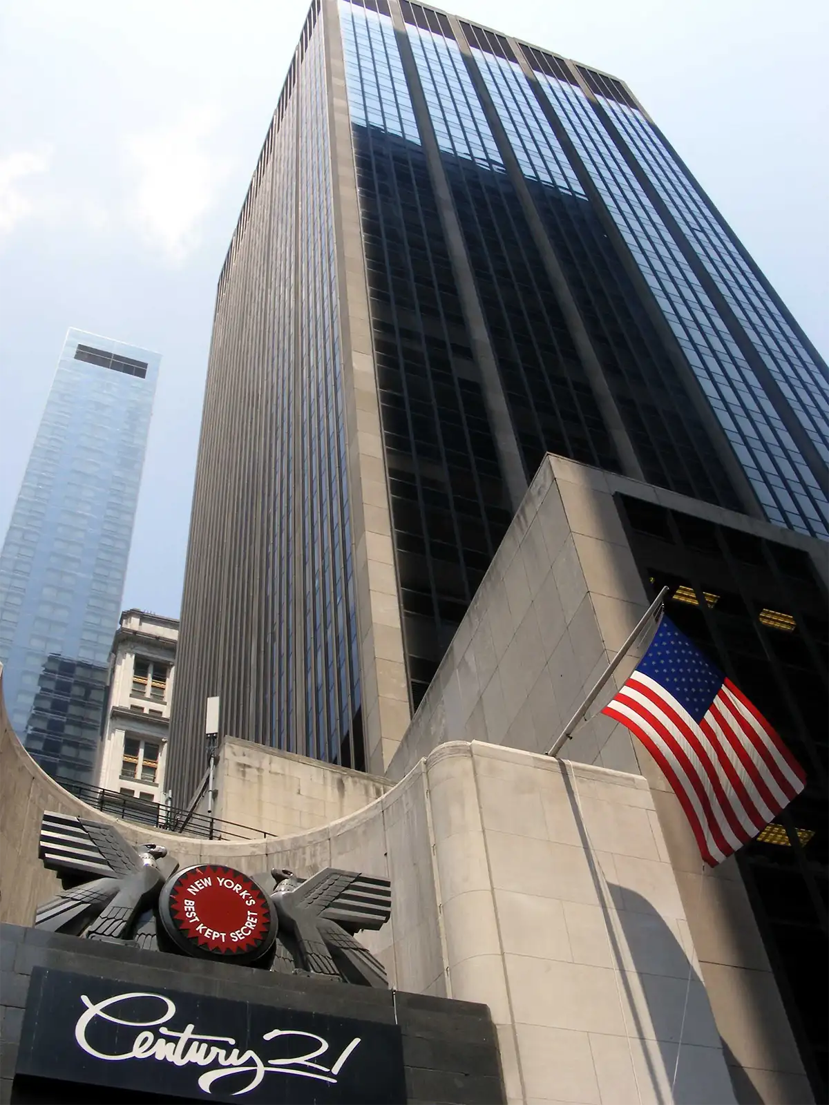 Entrée du grand magasin Century 21 et drapeau américain au pied d’une tour du sud de Manhattan