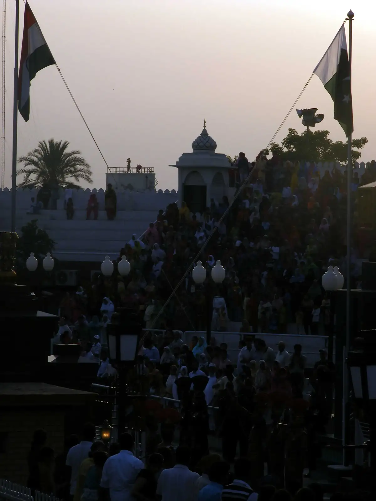 Foule en contre-jour sous les drapeaux indien et pakistanais, le soir à la frontière de Wagah