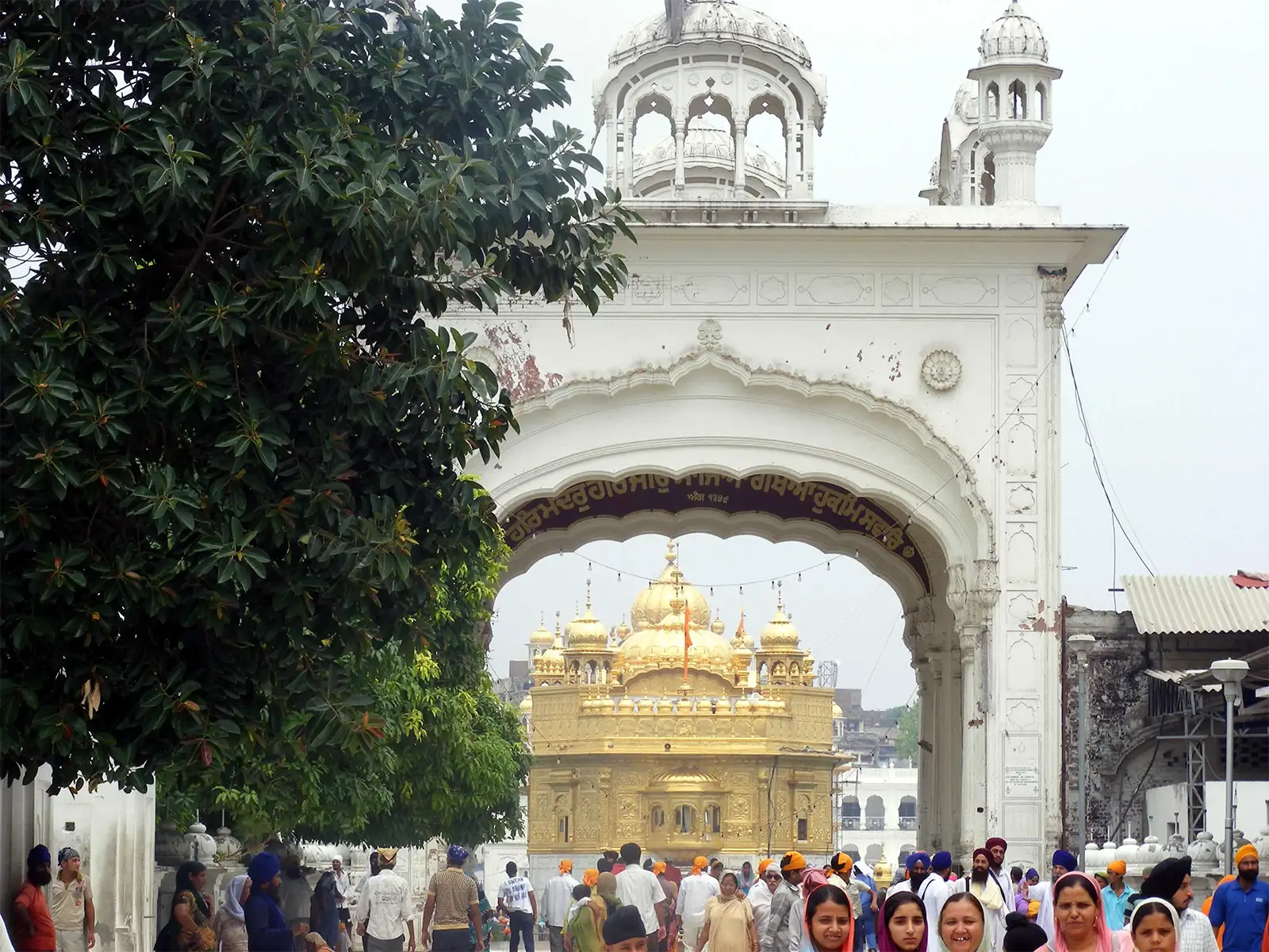 Le Temple d’Or d’Amritsar vu à travers une arche de marbre blanc, au milieu des pèlerins