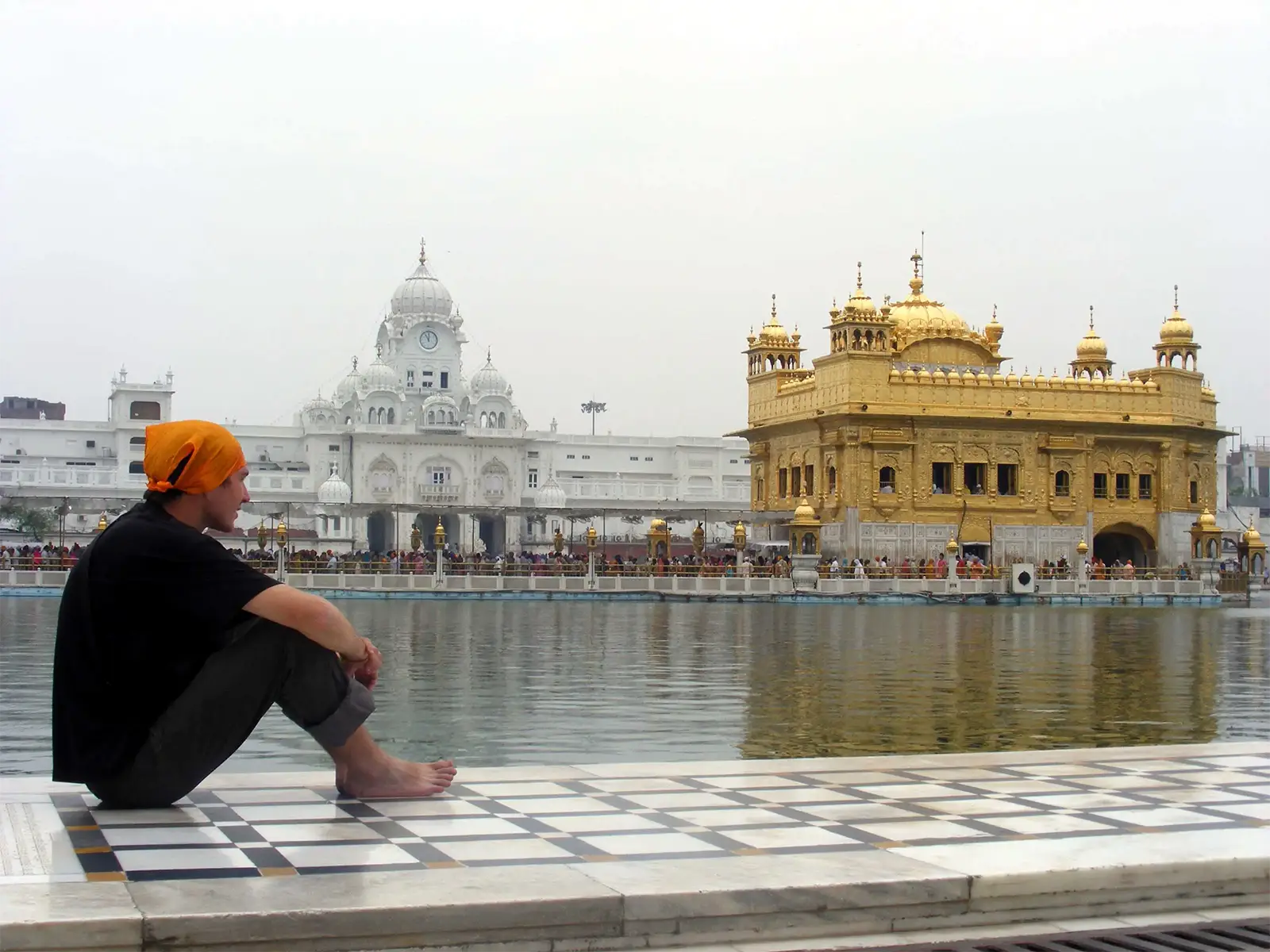 Un voyageur au foulard orange assis au bord du bassin sacré, face au Temple d’Or d’Amritsar