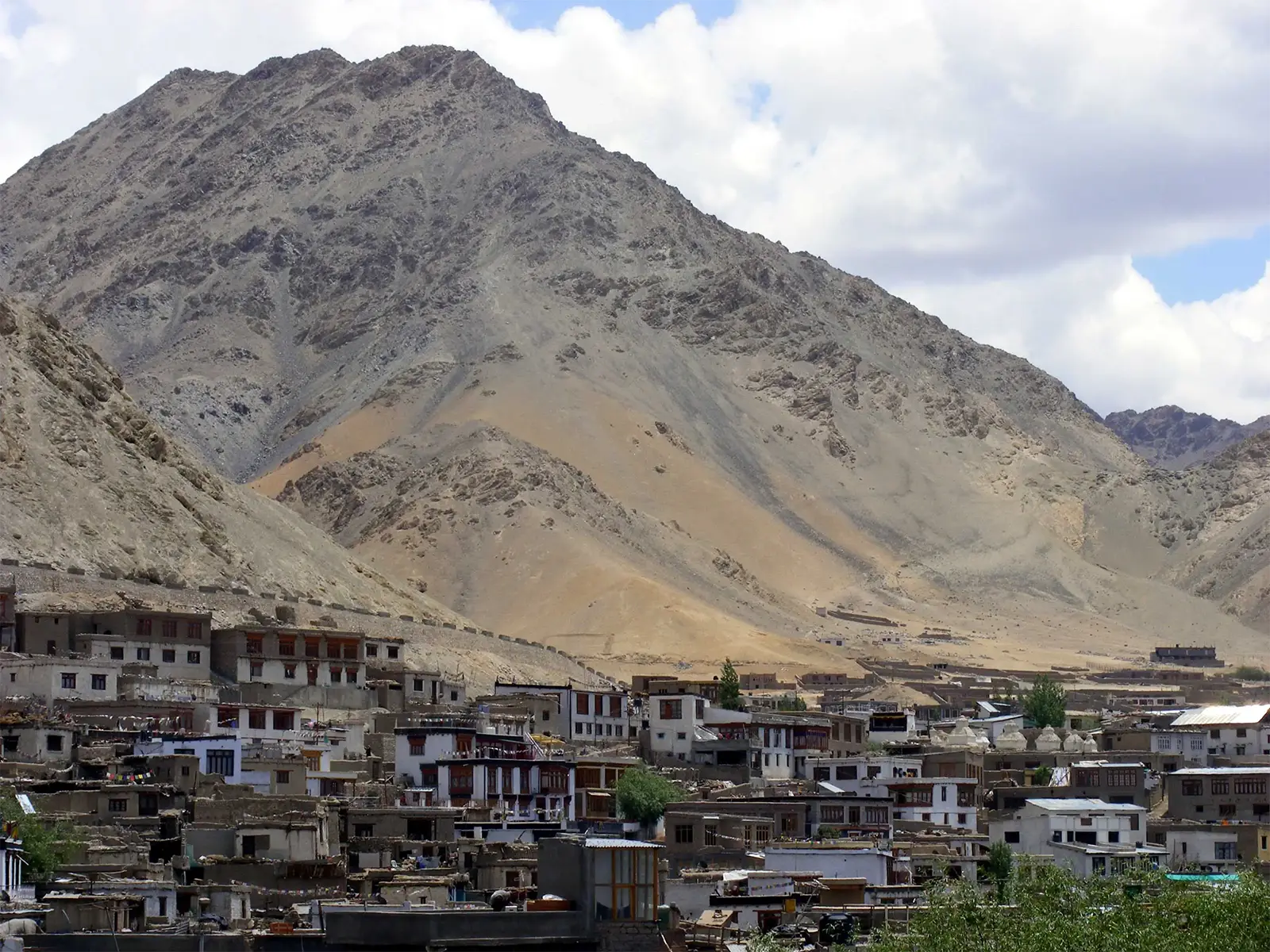 Maisons de Leh au pied d’une montagne aride du Ladakh, sous les nuages