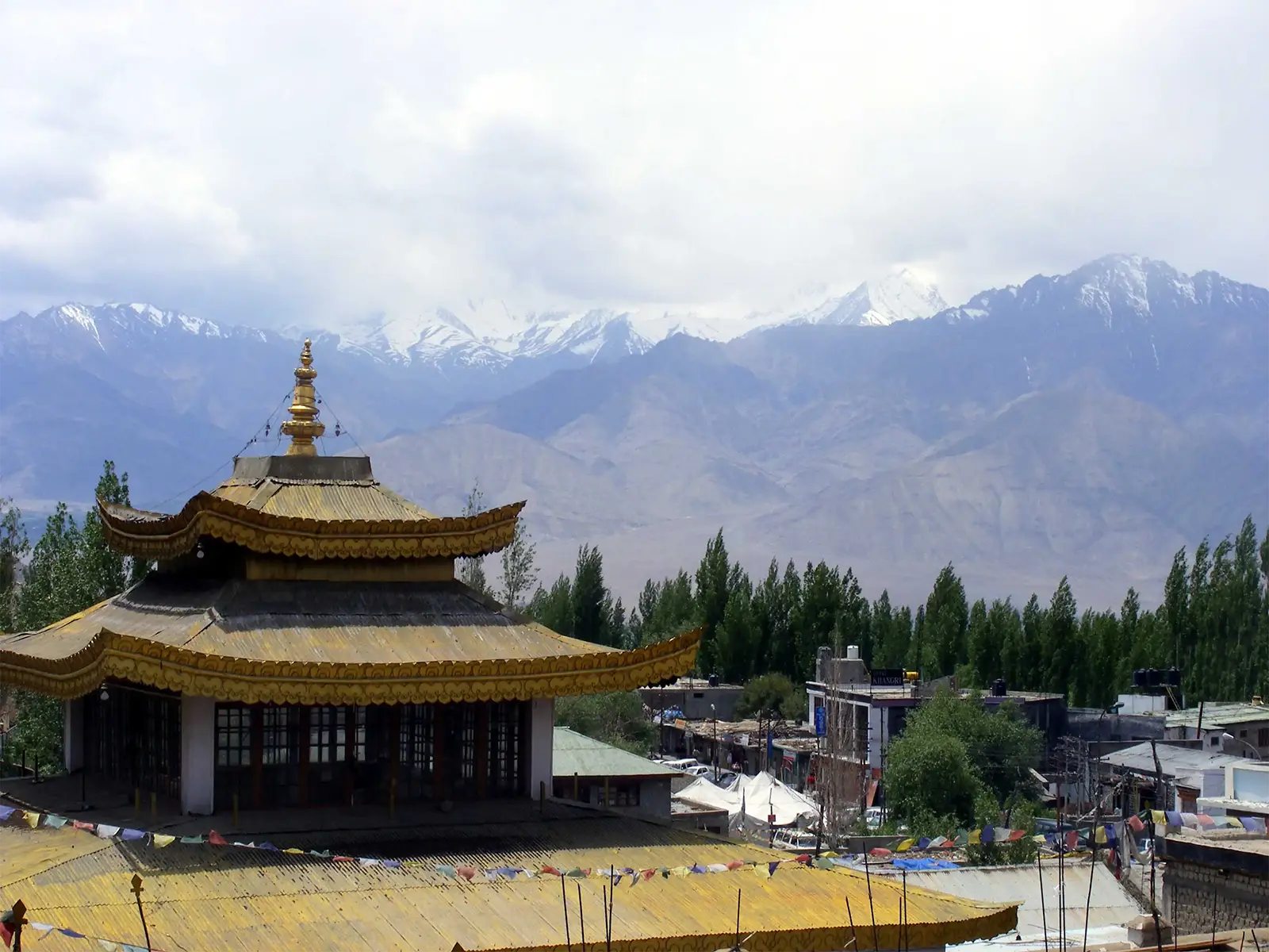 Toit doré d’un temple bouddhiste de Leh face aux sommets enneigés du Ladakh