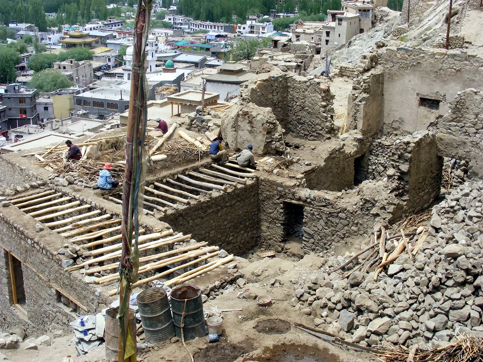 Ouvriers reconstruisant le toit d’une vieille maison de pierre dans la vieille ville de Leh
