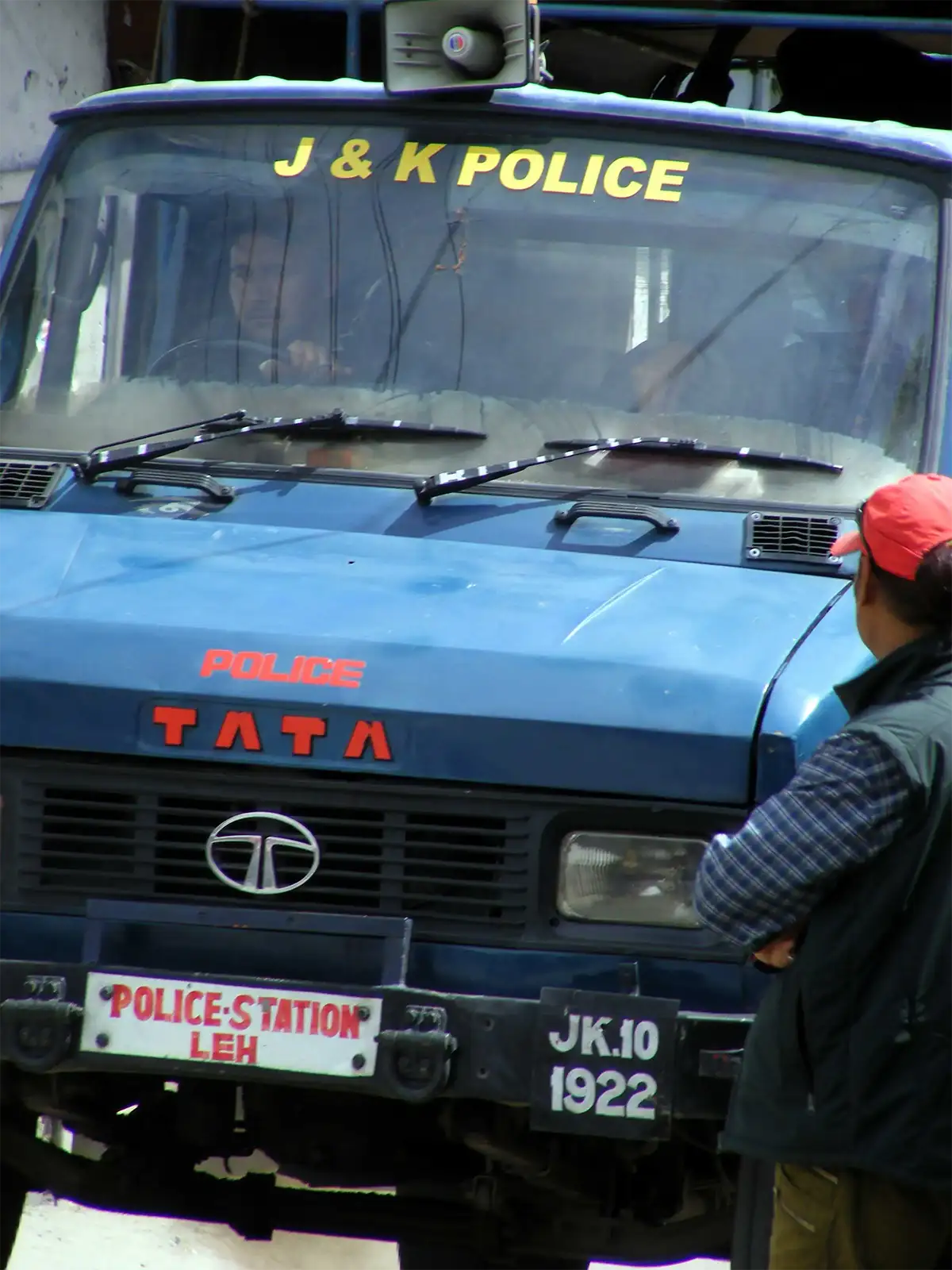 Camion bleu du commissariat de police de Leh et un passant à casquette rouge