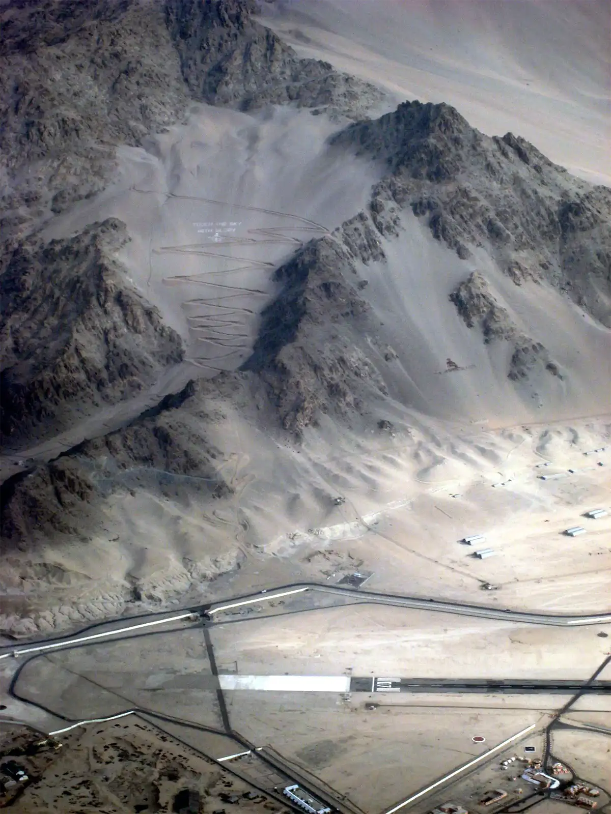 Piste de l’aéroport de Leh au pied des montagnes, vue d’avion à l’atterrissage
