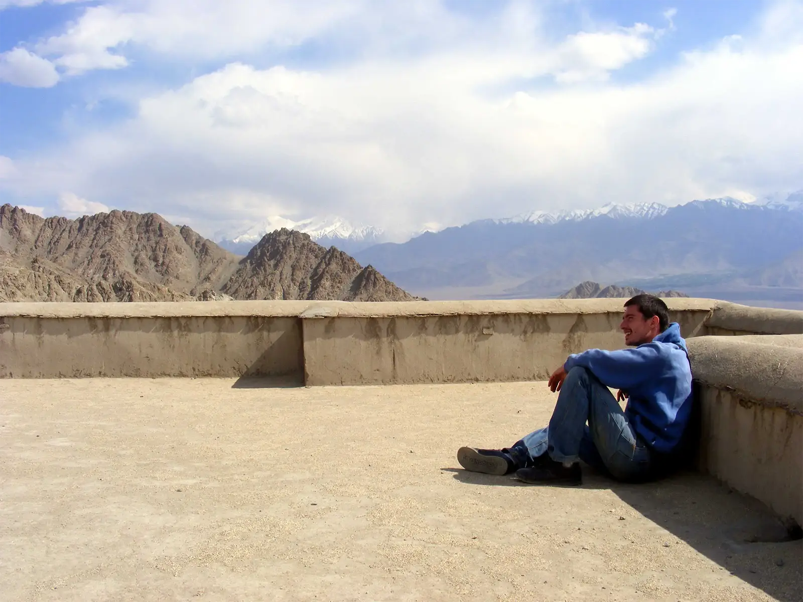Un voyageur assis sur une terrasse de Leh, face aux montagnes enneigées du Ladakh