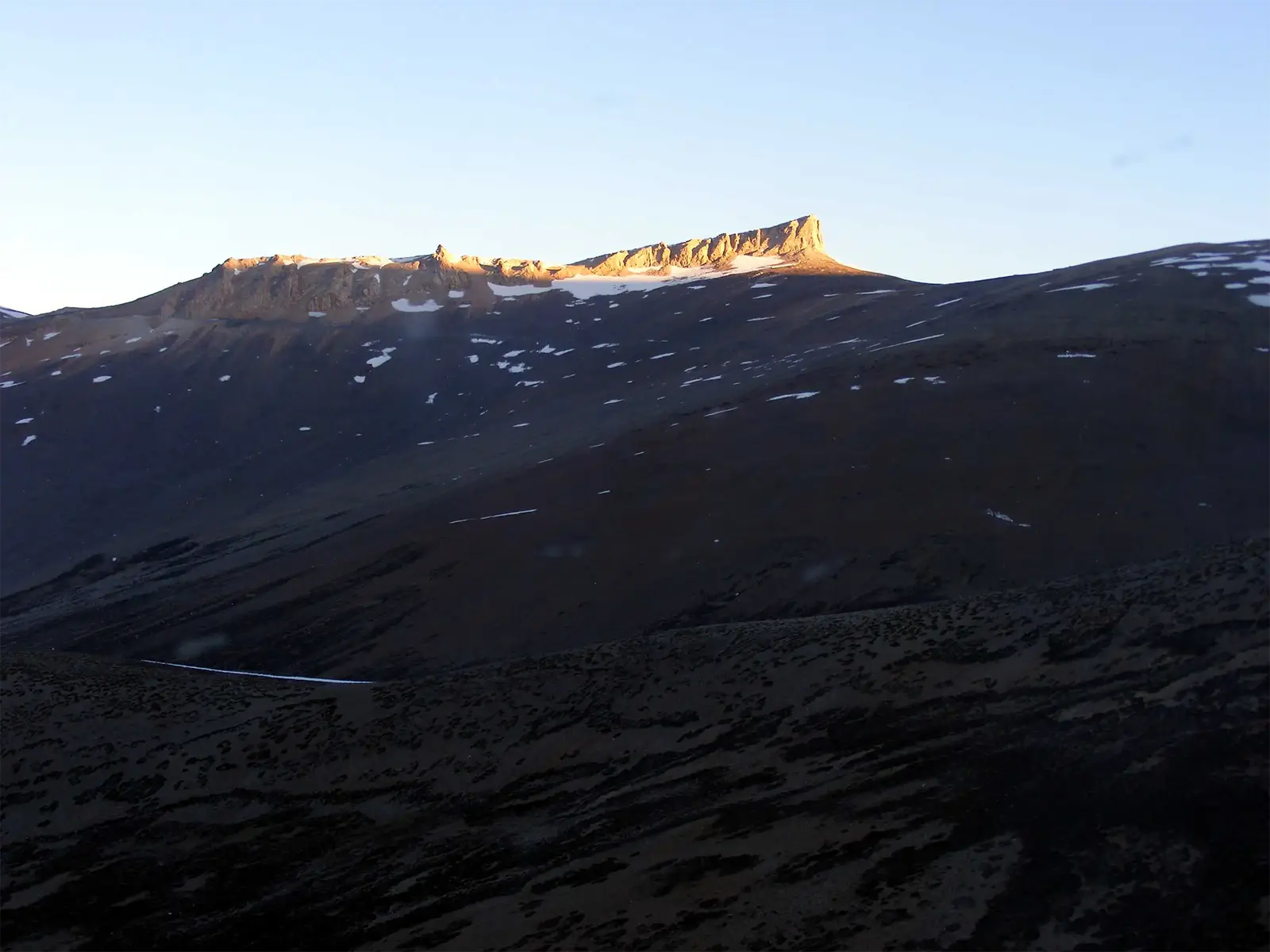 Plateau rocheux éclairé par une lumière rasante au-dessus de pentes sombres, route Leh–Manali