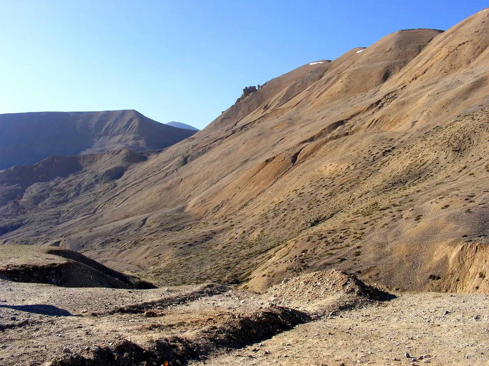 Pentes désertiques ocre sous un ciel bleu sur la route de Leh à Manali