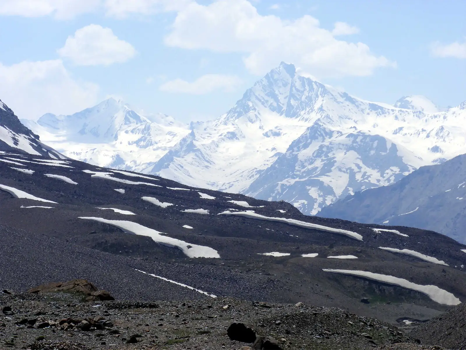 Sommet pointu enneigé derrière des pentes de neige fondante, sur la route de Leh à Manali