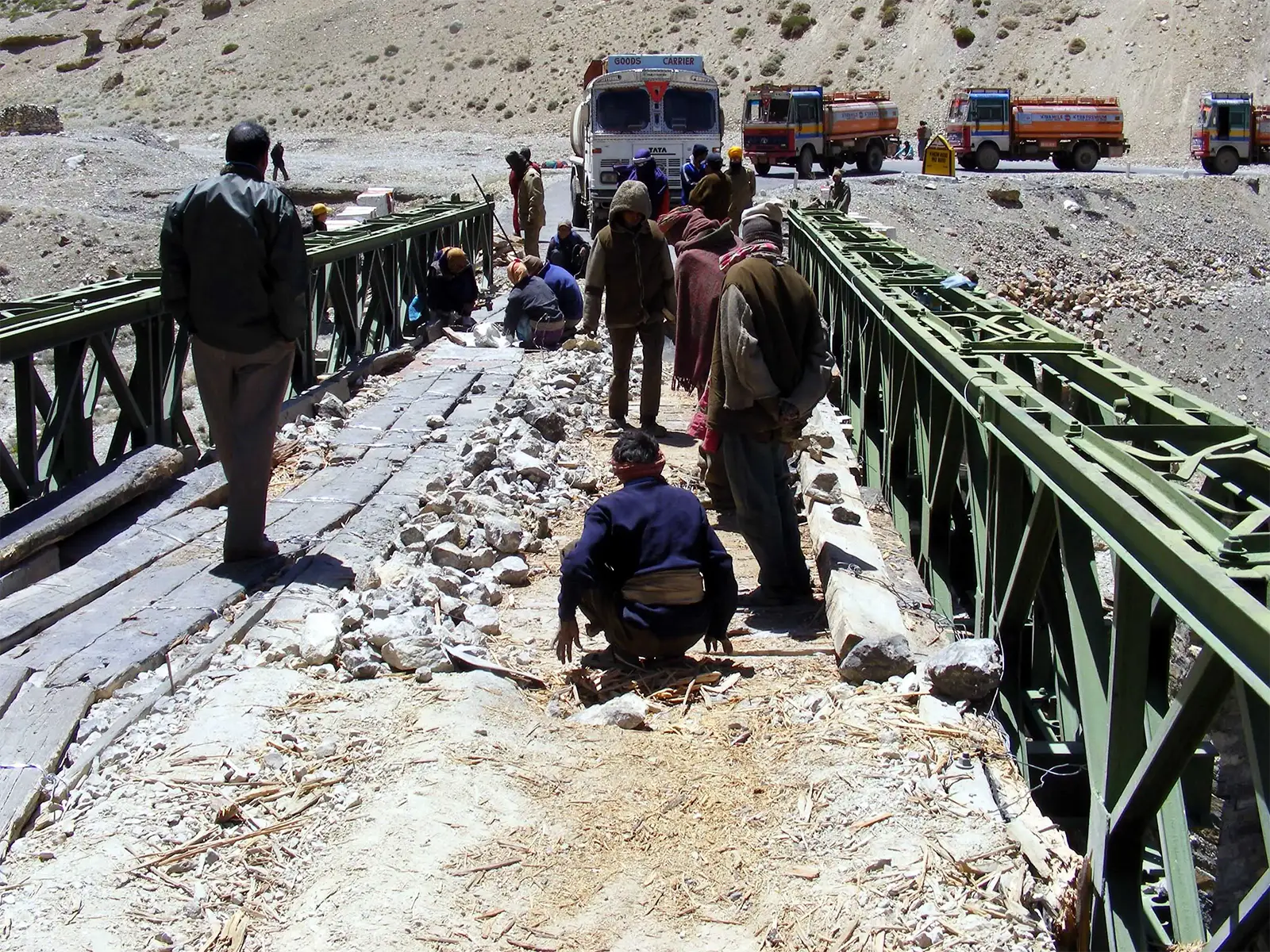 Ouvriers réparant un pont cassé devant les camions à l’arrêt, sur la route Leh–Manali