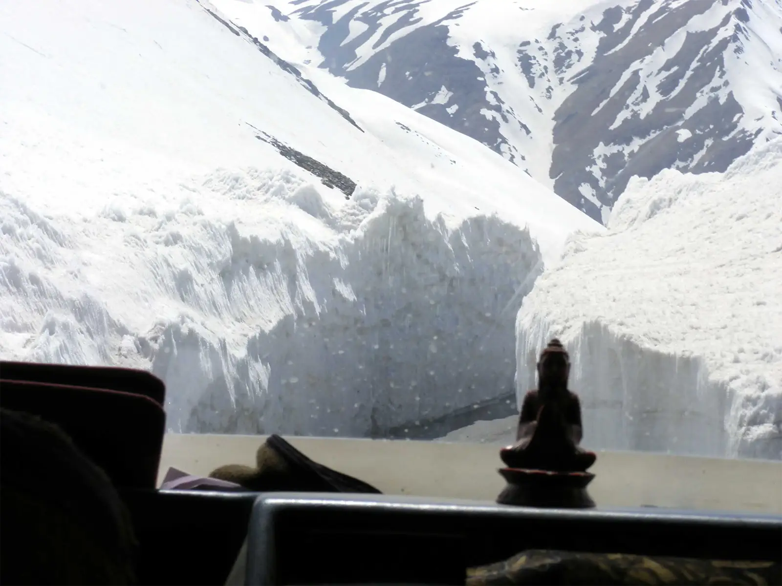 Murs de neige vus à travers le pare-brise, derrière une statuette de Bouddha, route Leh–Manali