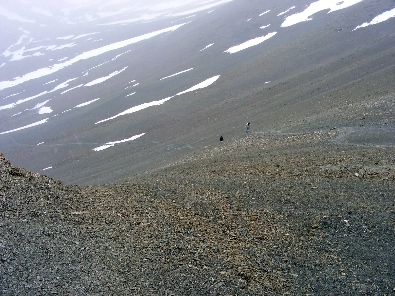 Deux randonneurs minuscules sur un immense pierrier au début de l’ascension du Stok Kangri
