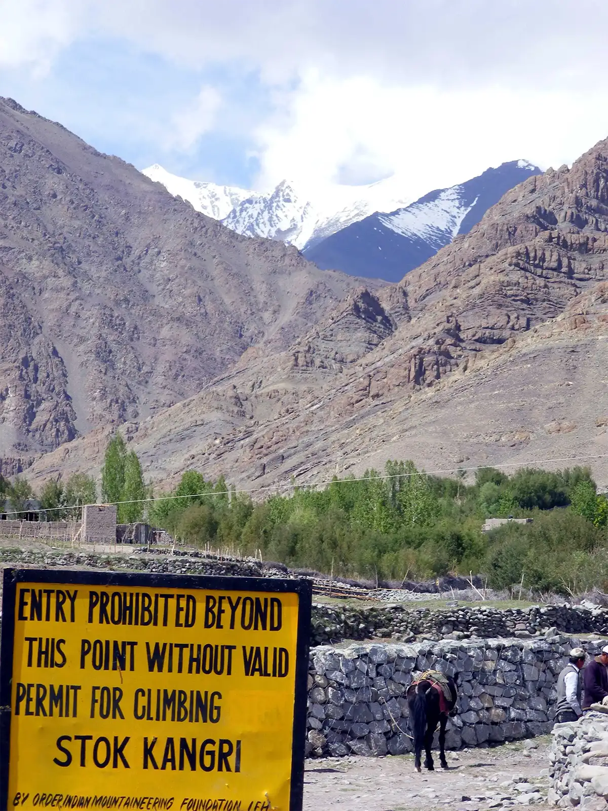 Panneau de permis d’ascension au départ du trek du Stok Kangri, sous les sommets enneigés