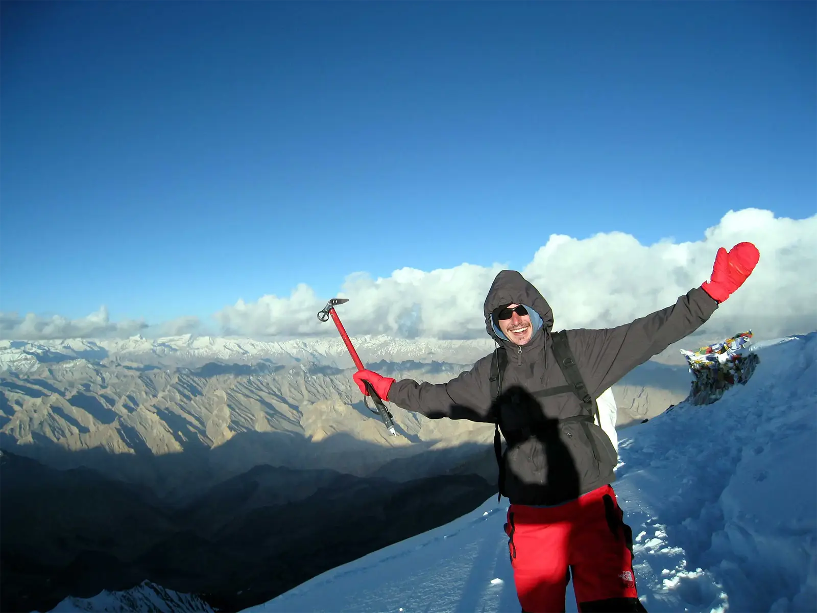 Un voyageur bras levés, piolet en main, au sommet du Stok Kangri à 6 153 m