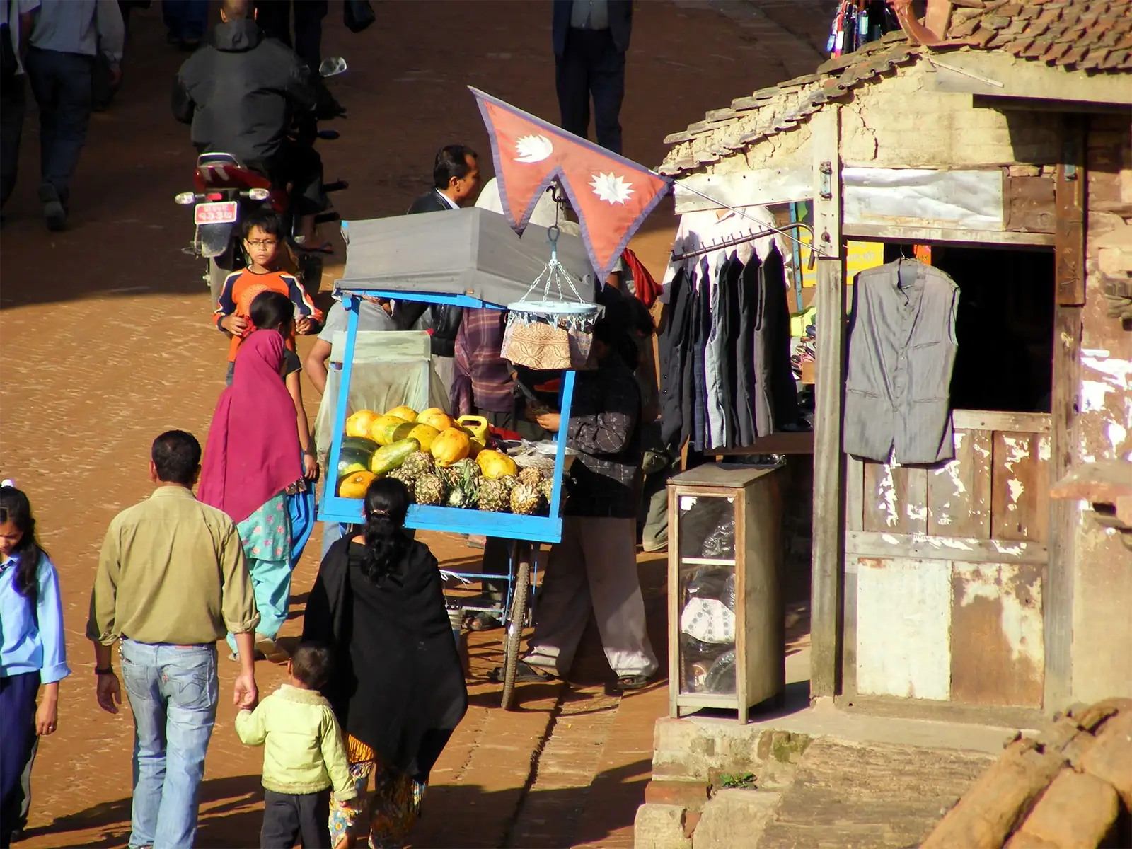 Charrette de marchand de fruits sous un drapeau népalais dans une rue animée de Bhaktapur
