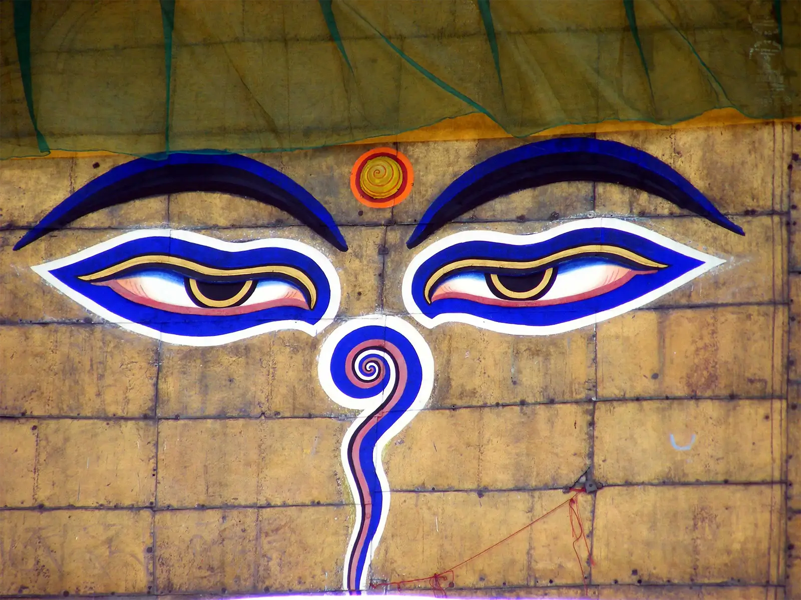 Les yeux de Bouddha peints en bleu sur la tour dorée d’un stupa de Katmandou