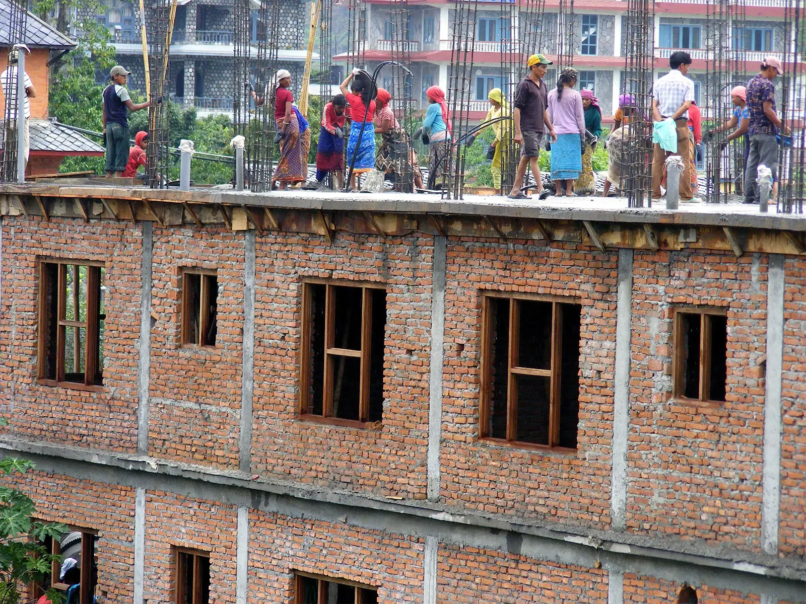 Ouvriers et ouvrières sur le toit d’un immeuble de briques en chantier à Pokhara