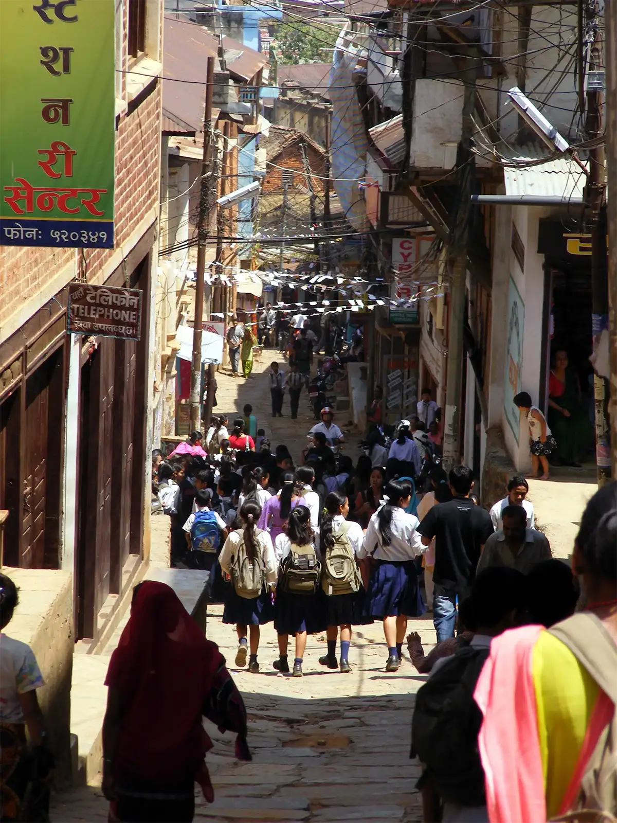 Écoliers en uniforme descendant une ruelle pentue et animée de Tansen