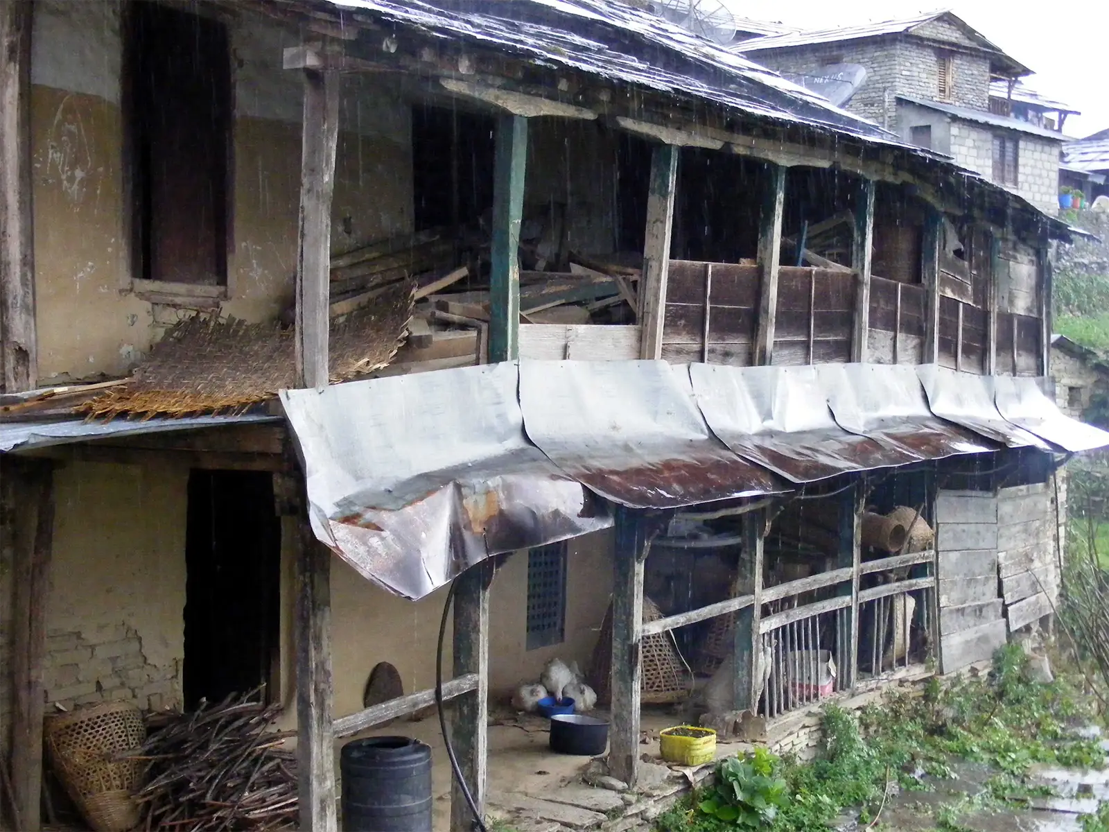 Maison de village en bois et pierre sous la pluie sur le trek des Annapurnas
