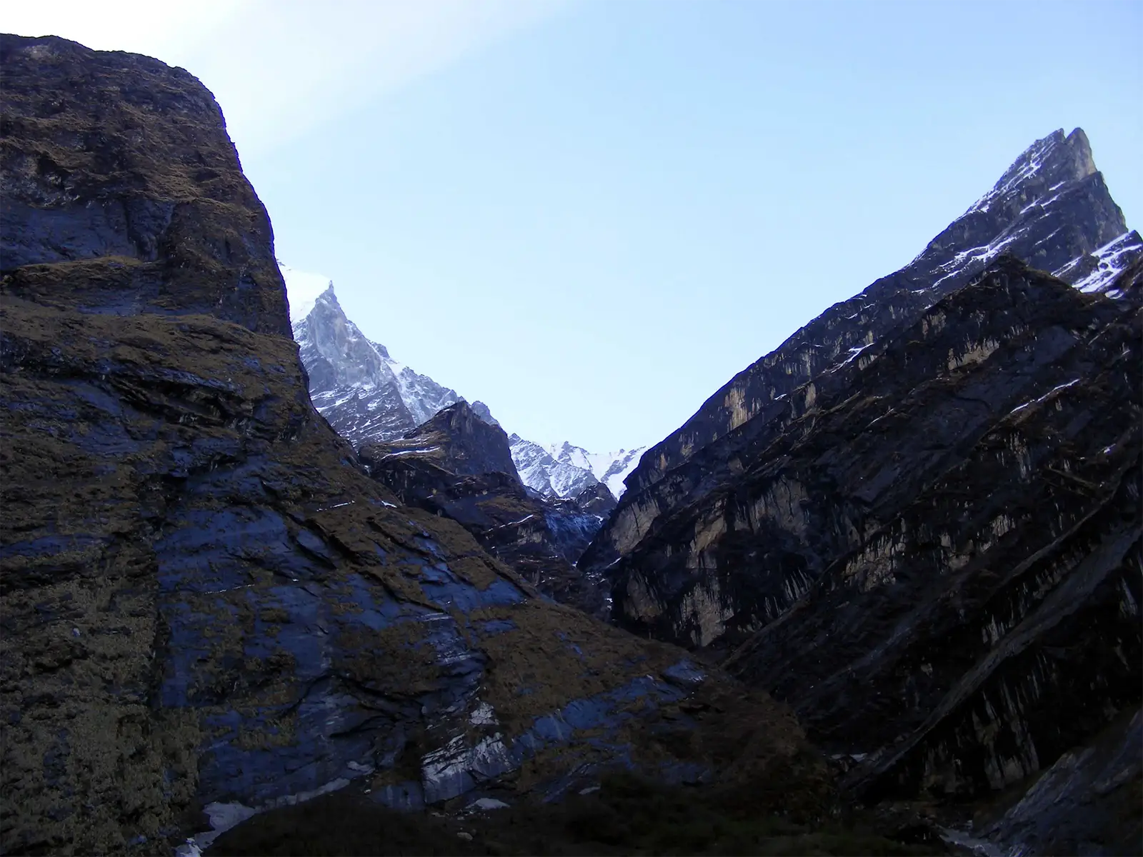 Parois rocheuses dans l’ombre et pics enneigés au soleil dans le sanctuaire des Annapurnas