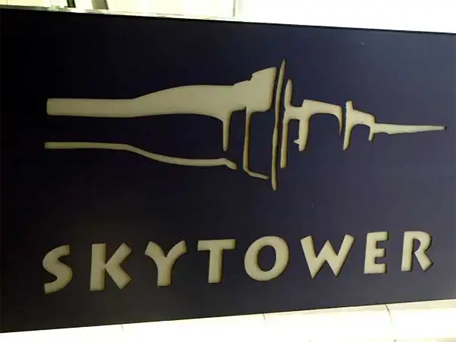 Logo de la Sky Tower découpé dans un panneau sombre à l’entrée de la tour à Auckland