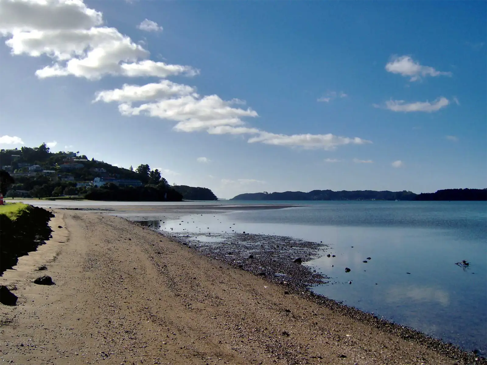 Plage de sable à marée basse le long d’une baie calme de la Bay of Islands, près de Paihia