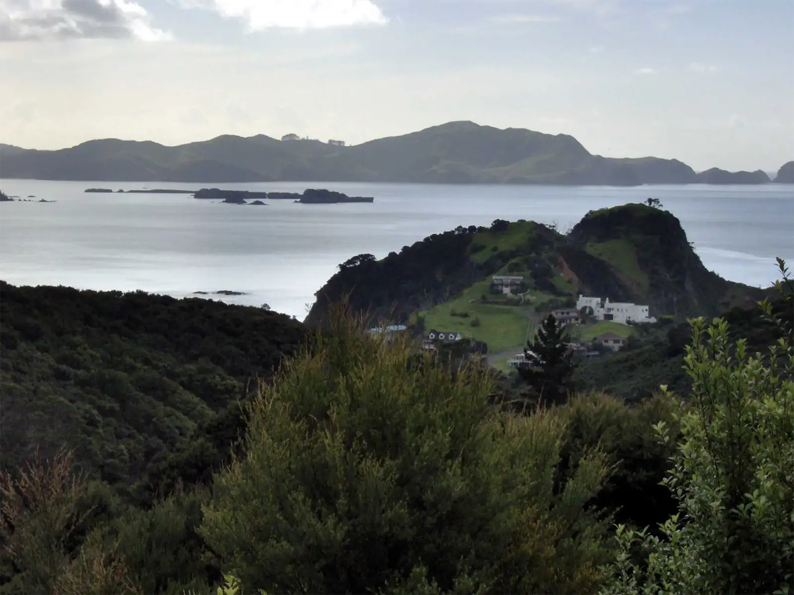 Villa blanche sur un promontoire vert face aux îlots de la Bay of Islands, vue des hauteurs