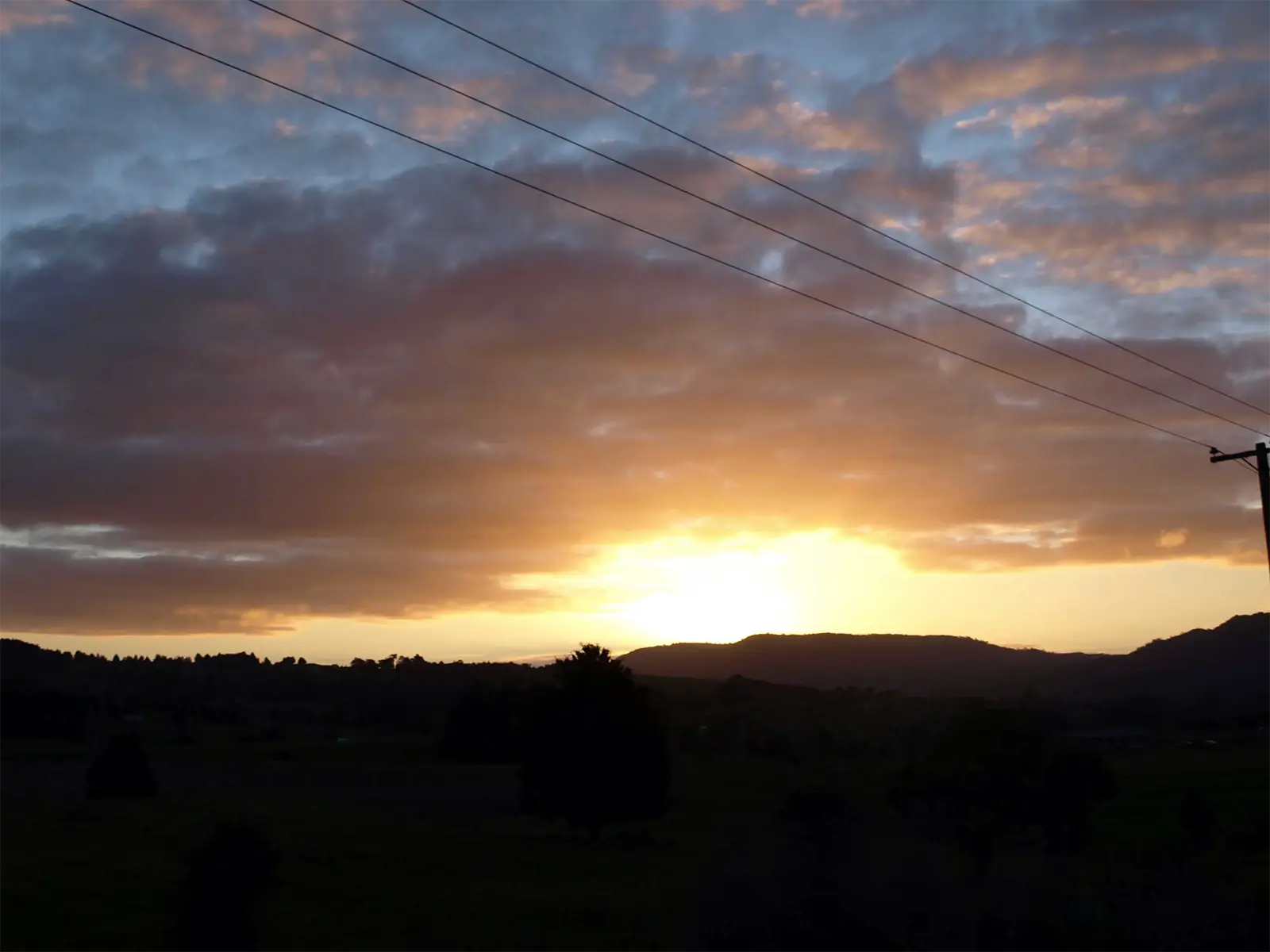 Ciel orangé au coucher du soleil sur les collines de l’extrême nord, sur la route du cap Reinga