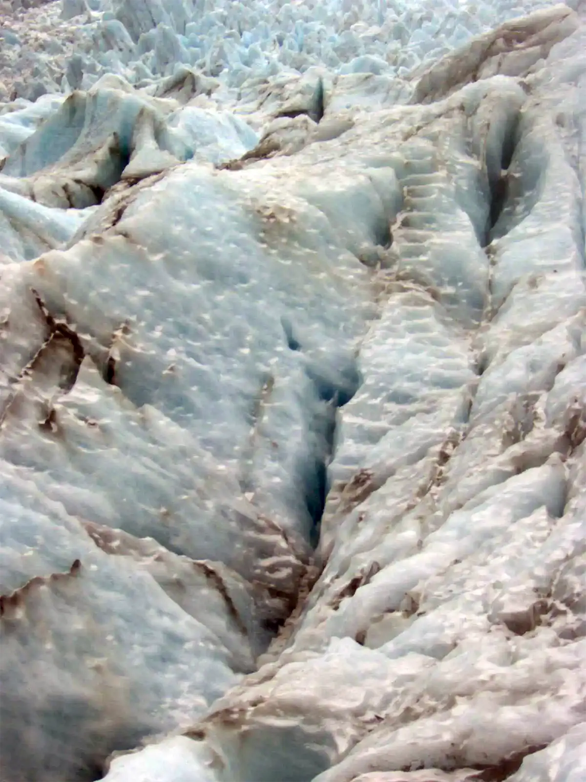 Crevasses et marches taillées dans la glace bleutée du glacier Fox, en gros plan