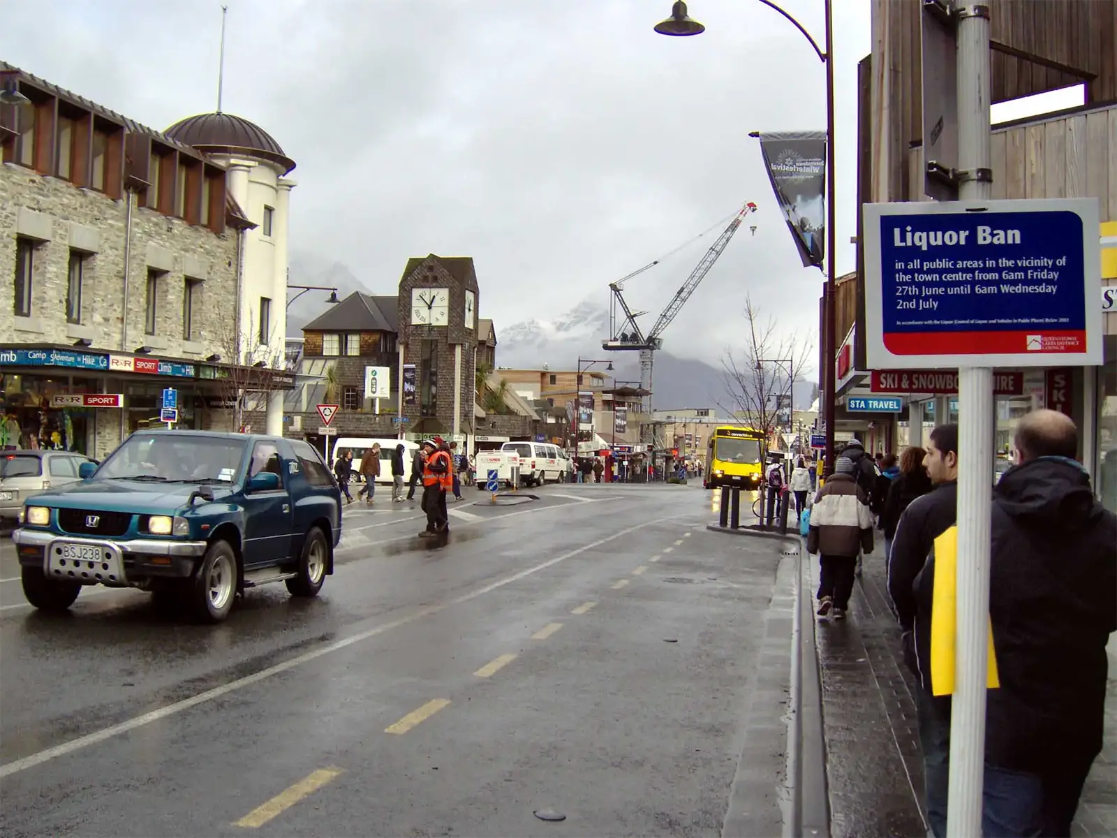 Rue du centre de Queenstown sous la pluie, avec un panneau d’interdiction d’alcool pour le Winter Festival