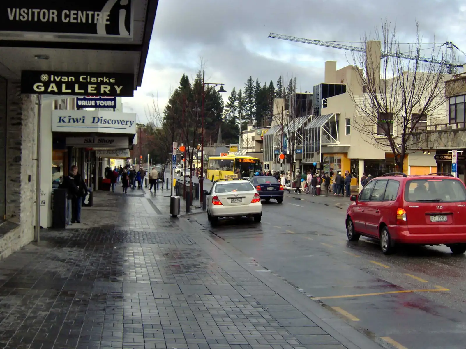 Trottoir mouillé, boutiques et Visitor Centre dans le centre-ville de Queenstown, par temps gris