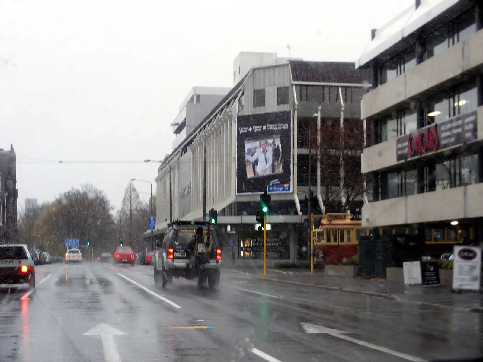 Rue de Christchurch sous la pluie, avec un tramway historique rouge et crème à l’arrêt