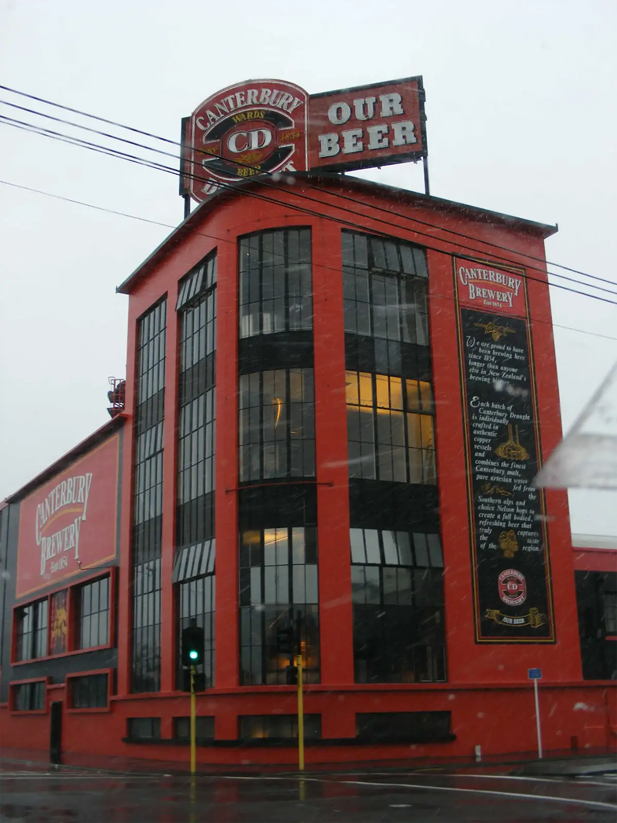 La brasserie Canterbury, bâtiment rouge aux grandes verrières sous la pluie à Christchurch