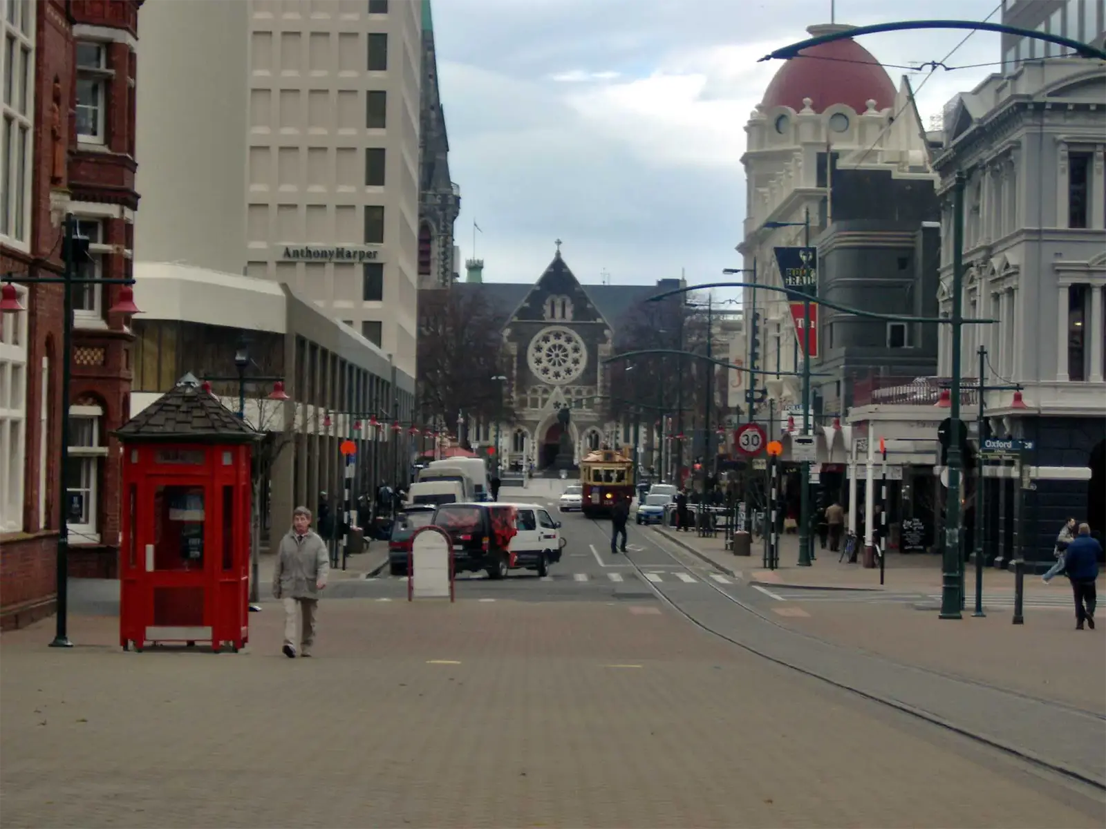 Rue piétonne du centre de Christchurch menant à la cathédrale, avec un tramway et une cabine rouge