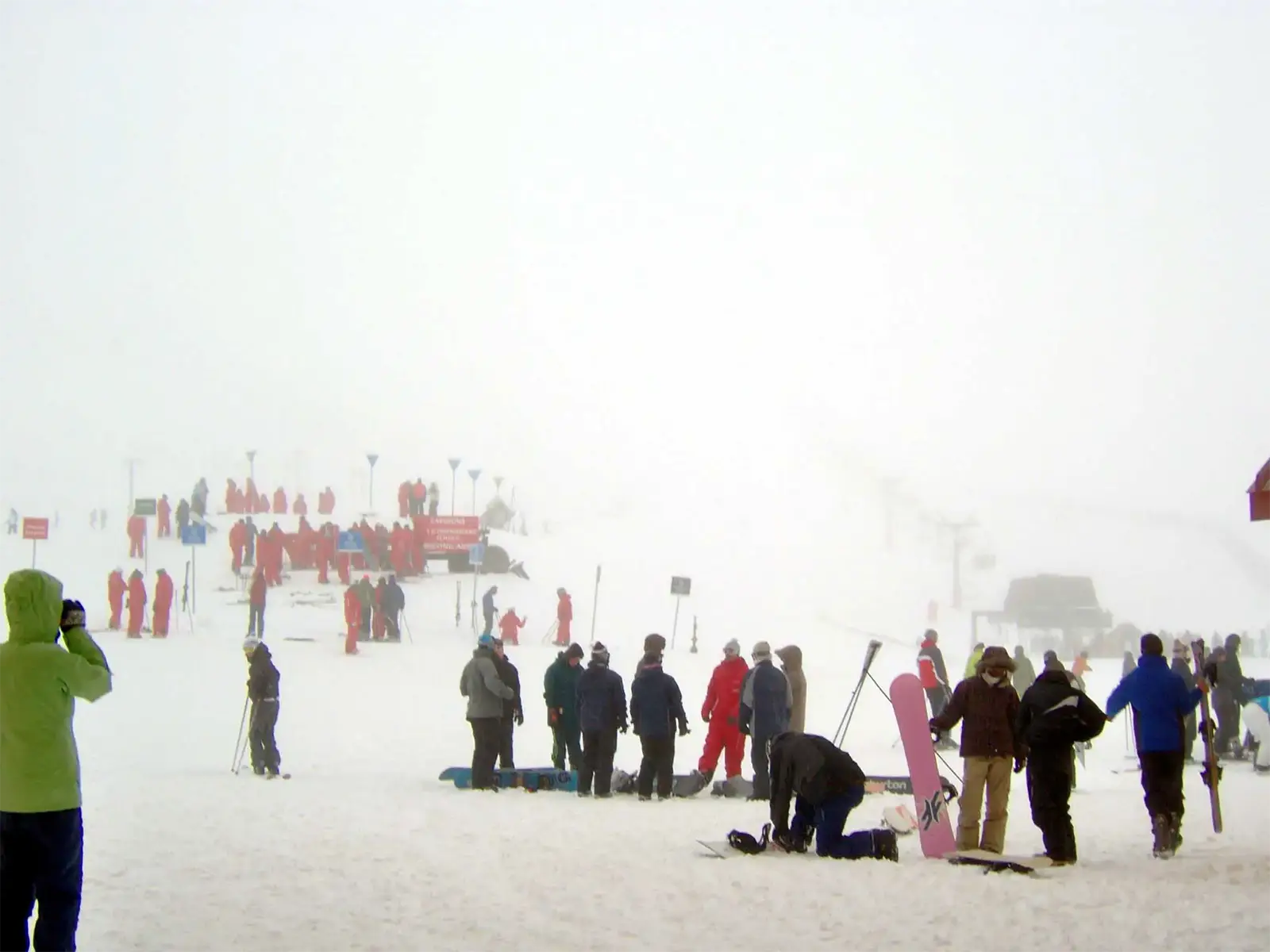 Skieurs et snowboardeurs dans un épais brouillard au pied des pistes d’une station de ski près de Wanaka