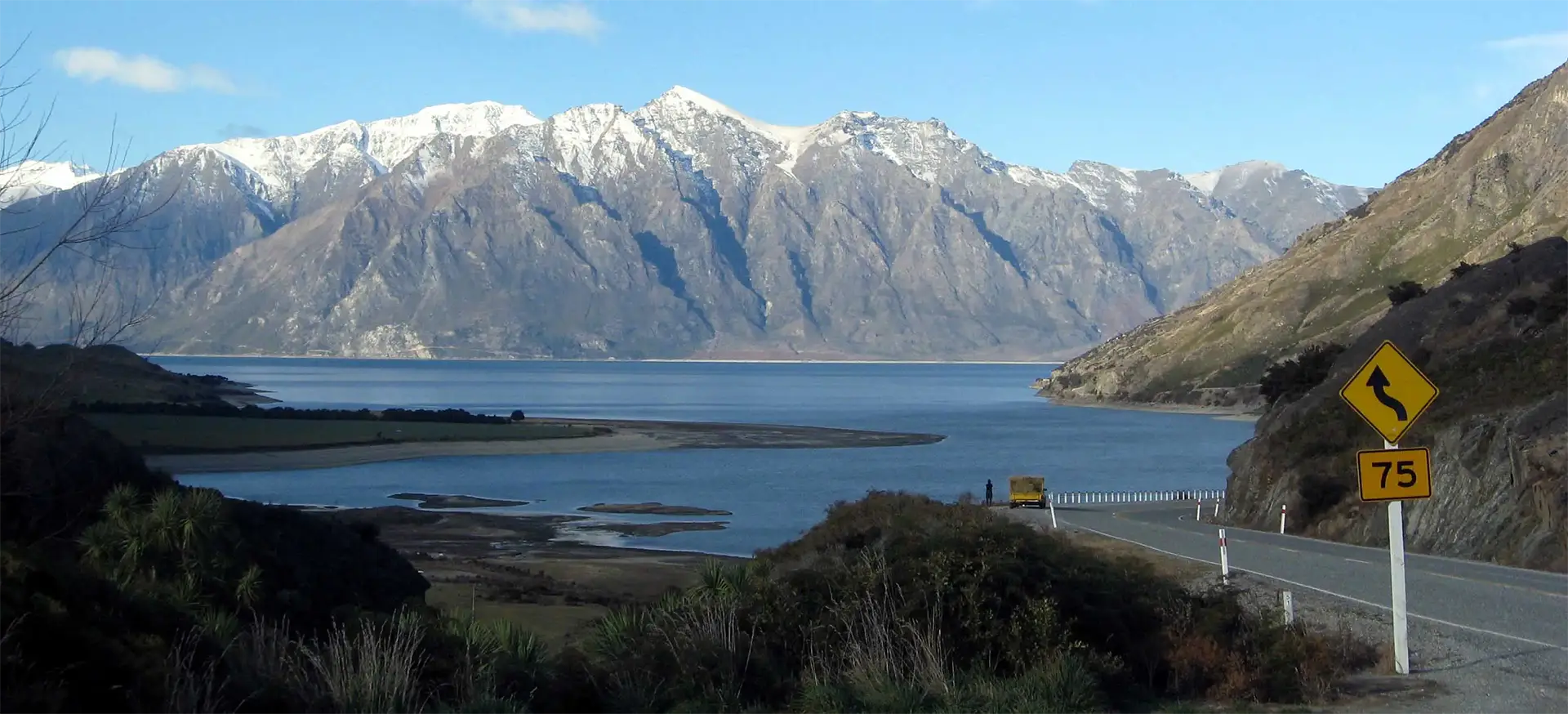 Lac bordé de montagnes enneigées au bord de la route sinueuse entre Makarora et Wanaka