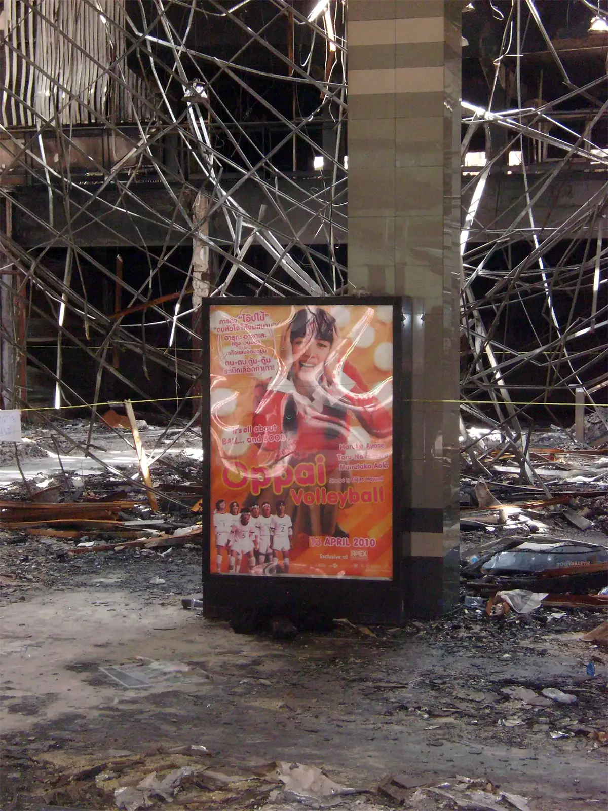 Affiche publicitaire intacte au milieu des structures tordues d’un centre commercial incendié à Ratchaprasong