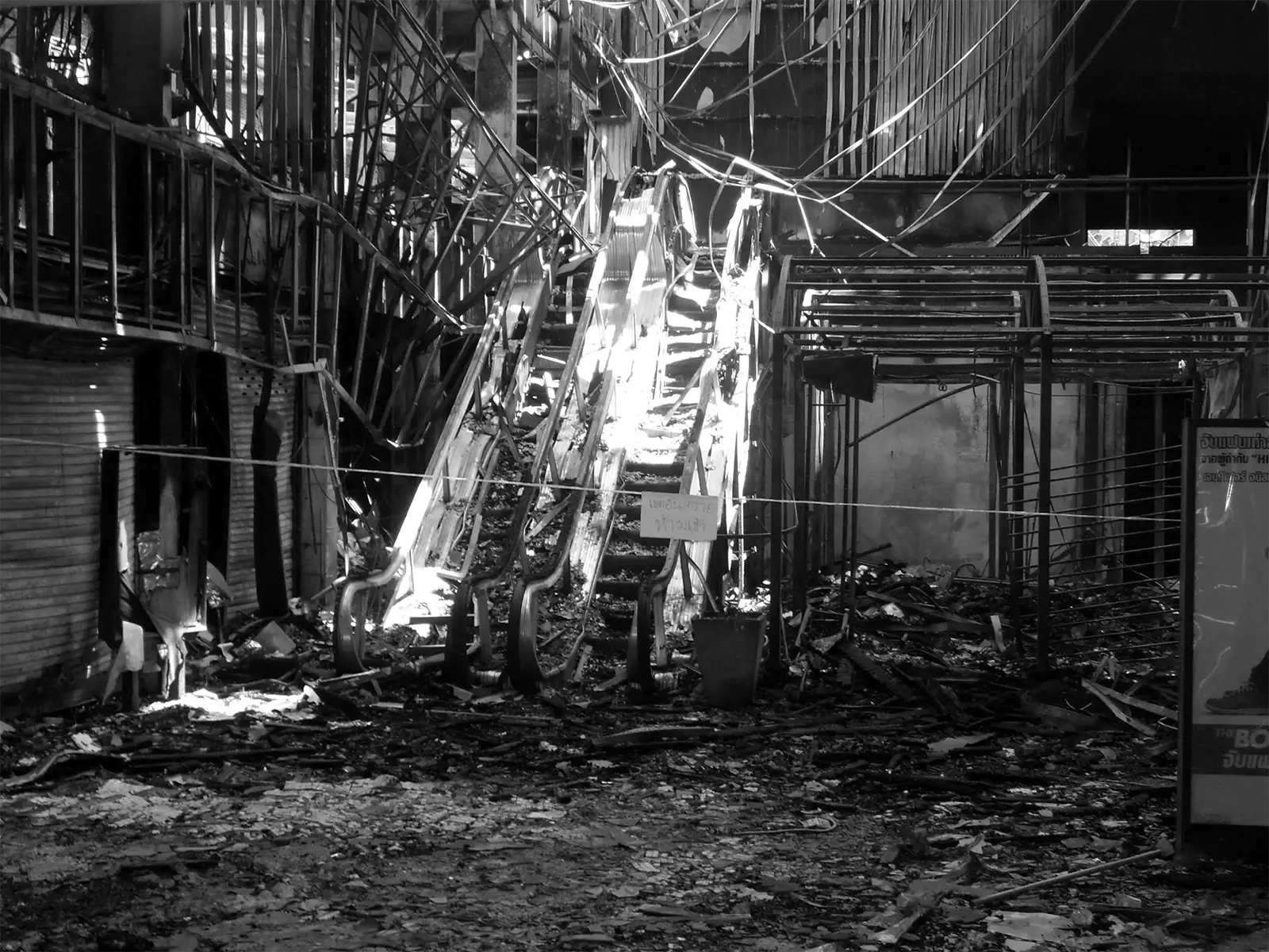Escalators en ruines dans un centre commercial incendié de Ratchaprasong, en noir et blanc