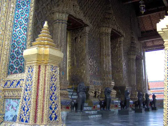 Lions de bronze et piliers en mosaïque dorée le long de la chapelle du Wat Phra Kaew à Bangkok